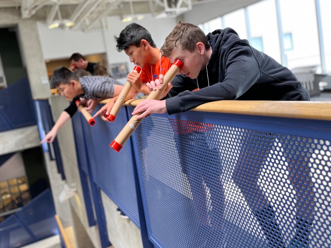 Middle school aged kids looking through hand-made telescopes at NKU.