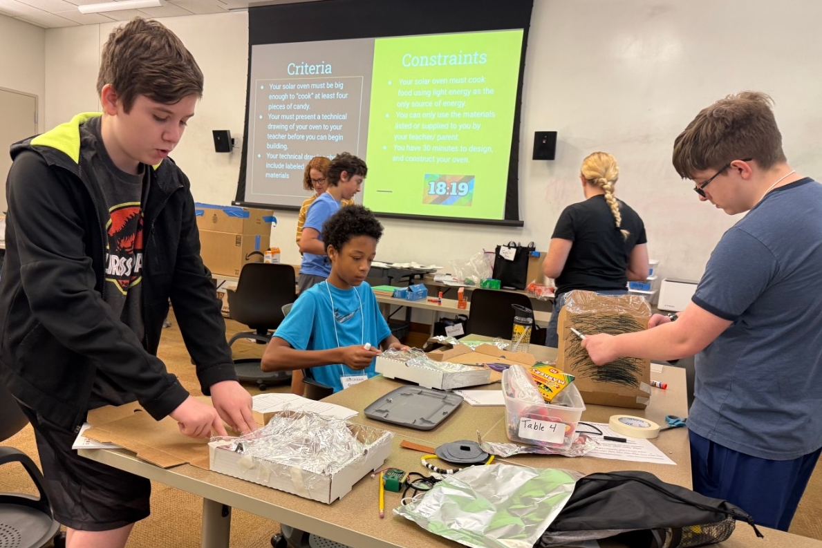 Several middle school children intently build solar ovens using common household materials..