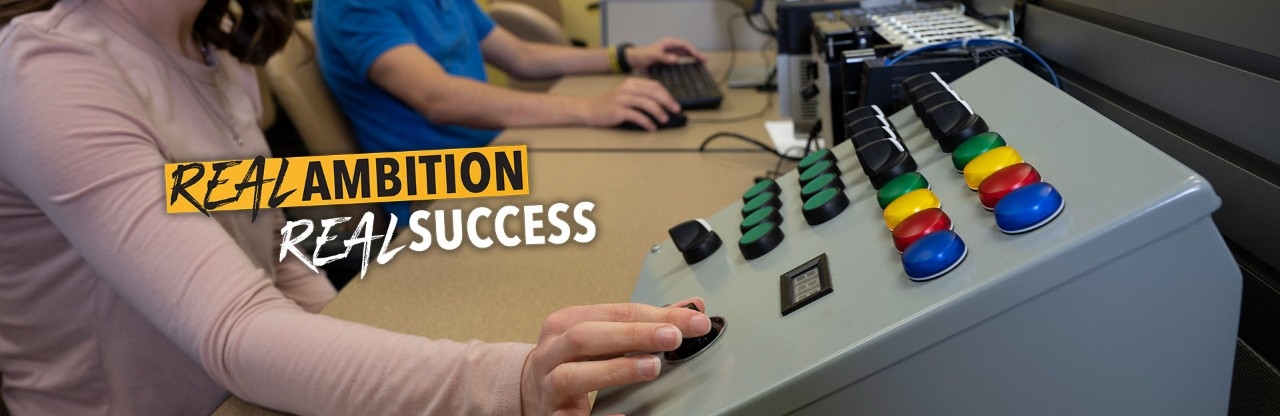 Photo of students using engineering instruments with a tagline that says, "Real Ambition, Real Success"
