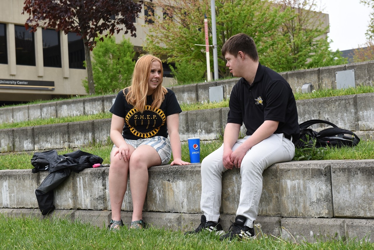 Female Shep Peer mentor sitting outside chatting with a male Shep student.