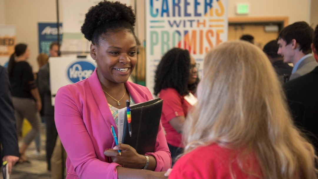 A student is greeted by a career fair attendee