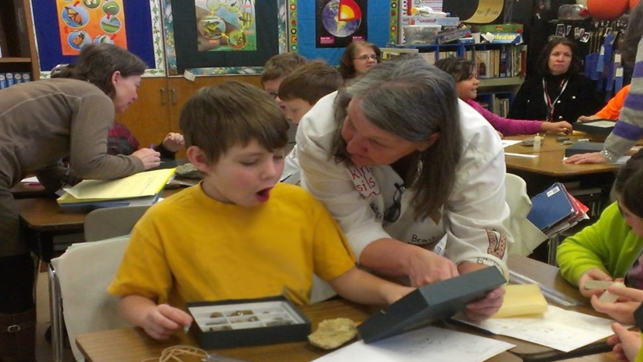 Primary school teacher and student talking in a classroom