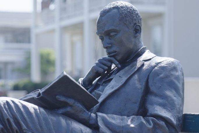 Stock image, statue of a man reading on a bench. 